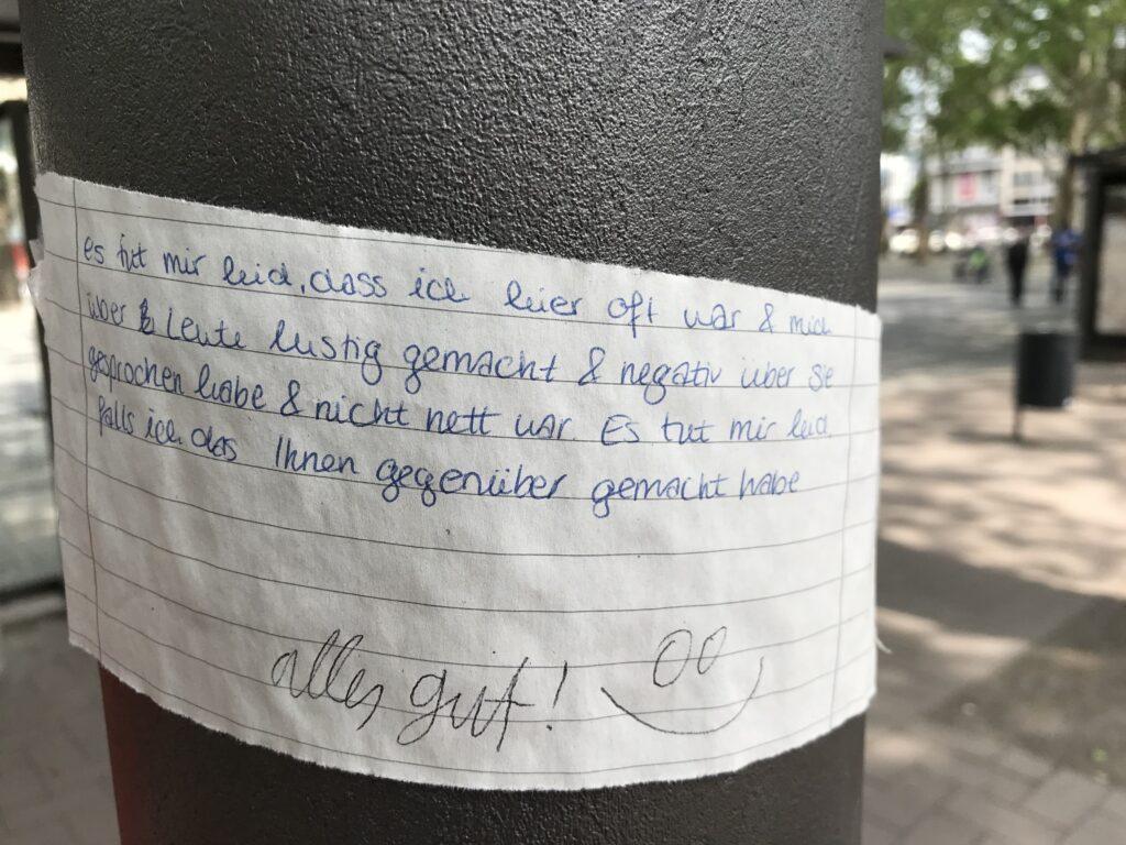 Liebe geht raus: An einem Laternenmast klebt ein Zettel, auf diesem steht in Handschrift:
"Es tut mir leid, dass ich hier oft war & mich über Leute lustig gemacht & negativ über sie gesprochen habe & nicht nett war. Es tut mir leid, falls ich das Ihnen gegenüber gemacht habe"
Darunter hat jemand geschrieben "alles gut!" und ein Smiley gemalt.